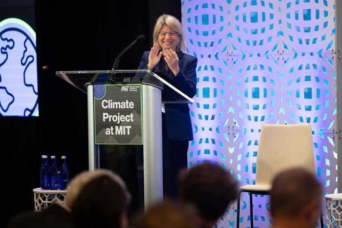 Sally Kornbluth on stage. A sign on the podium says "Climate Project at MIT."